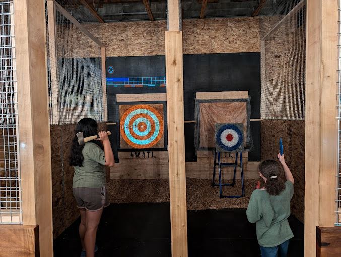 Two guests throw axes at bullseye targets in the wooden lanes in Port Orchard.